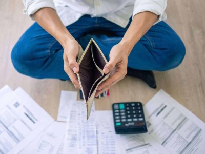 A businessman who is sitting on the floor of the house opening the wallet but have to pay debt Calculation of large amounts of expenses. Debt concepts