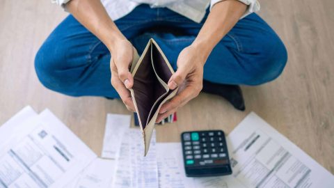 A businessman who is sitting on the floor of the house opening the wallet but have to pay debt Calculation of large amounts of expenses. Debt concepts