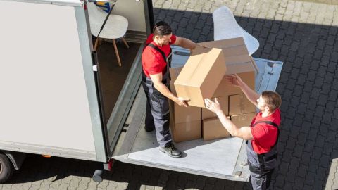 An Overhead View Of A Male Movers Unloading The Cardboard Boxes Form Truck On Street